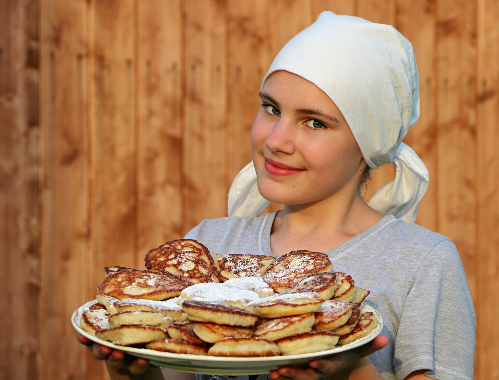 woman in grey crew neck shirt holding a white ceramic plate with pancakes